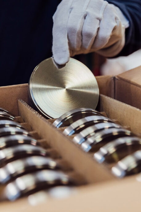 An employee holds a dental disk in his hand.